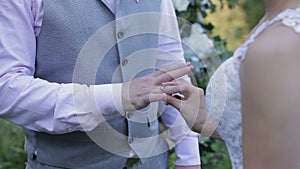 Bride wears ring on groom`s finger. Gold wedding rings and hands of just married couple. The bride and groom exchange