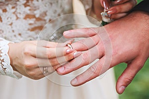 Bride wears a ring on the hand of the groom on wedding ceremony outdoor