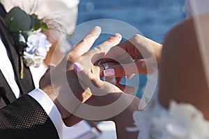 Bride wears wedding ring to groom on background of sea