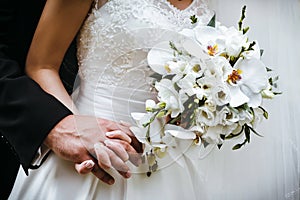 Bride with wedding bouquet of white orchids and groom holding ea