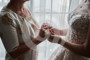 Bride on wedding day holding her mother`s hands. Concept of relationship between moms and daughters