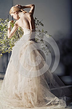 Bride in wedding dress behind bush with flowers