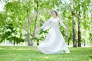 Bride in wedding dress dancing in park