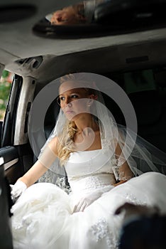 Bride in wedding dress sits in limousine