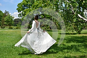 Bride whirls in a white dress in the summer park