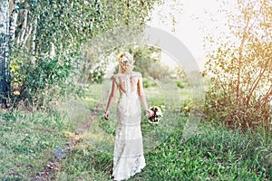 Bride in white dress with a bouquet is walking along.