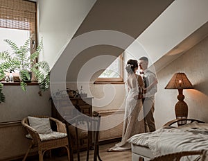 Bride in white dress and groom in suit, posing in white Studio