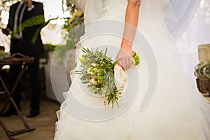 Bride in white dress hold wedding boquet in her hand