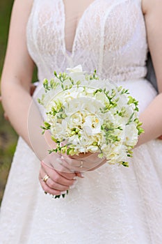 The bride in a white dress holds a bouquet of lisianthus with white roses.Wedding day concept