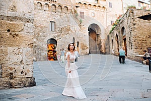 A bride in a white dress in the old town of San Gimignano.A girl walks around the city in Italy.Tuscany