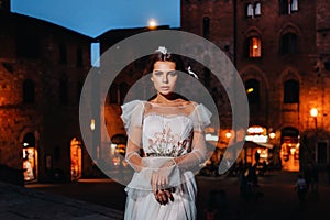 A bride in a white dress in the old town of San Gimignano.A girl walks around the city in Italy.Tuscany