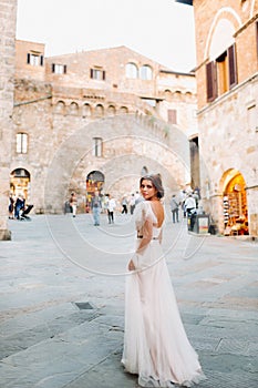 A bride in a white dress in the old town of San Gimignano.A girl walks around the city in Italy.Tuscany