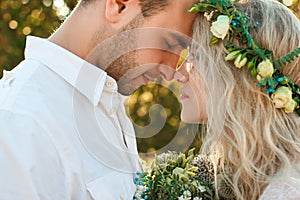 Bride in white dress and wreath and groom portrait in sunny summer day. Rustic outdoor wedding concept