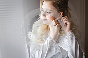 Bride in white peignoir wearing earrings