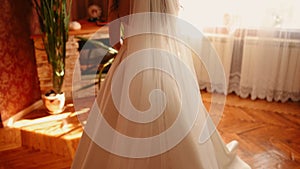 bride in white silk wedding dress and long veil moves away from camera.