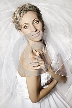 Bride in white veil looking and smiling at camera