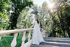 Bride in white wedd dress with bouquet in hand walking down stairs