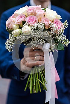 The bride in a white wedding dress is holding a bouquet of white flowers - peonies, roses. Wedding. Bride and groom. Delicate