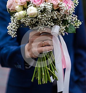 The bride in a white wedding dress is holding a bouquet of white flowers - peonies, roses. Wedding. Bride and groom. Delicate