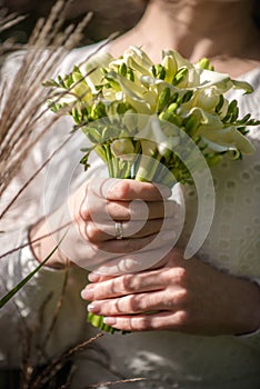 The bride in a white wedding dress is holding a bouquet of white flowers - peonies, roses. Wedding. Bride and groom. Delicate