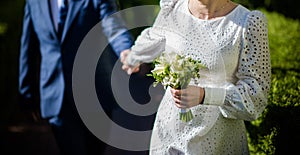 The bride in a white wedding dress is holding a bouquet of white flowers - peonies, roses. Wedding. Bride and groom. Delicate
