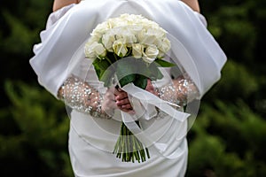 The bride in a white wedding dress is holding a bouquet of white flowers - peonies, roses. Wedding. Bride and groom. Delicate