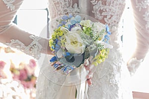 Bride in white wedding dress holding flower bouquet for elegant marriage ceremony concept