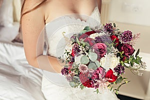 Bride in white wedding dress holding lilac wedding bouquet