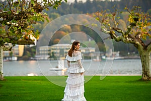 A bride in a white wedding dress in a park in an Austrian town with large trees at sunset