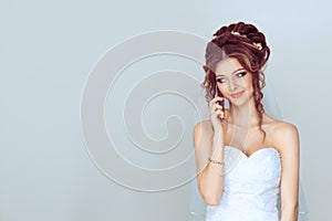 Bride, woman, girl, talking at mobile phone looking to the left side. isolated light blue background with copy space