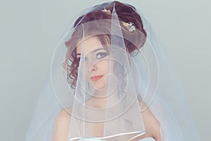 Bride Woman Portrait. Closeup portrait smiling happy young spouse looking through bridal veil isolated light blue wall background