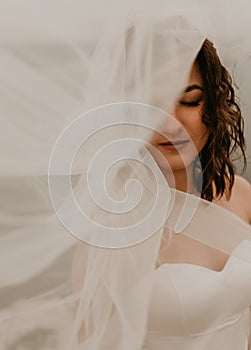 bride woman with short haircut in white wedding corset dress strapless and with a long chiffon veil on head