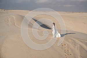 bride woman walking on sand dunes in desert