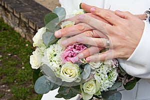 Bride woman in white marriage dress holding in hand wedding bouquet flowers with groom hands marriage rings golden