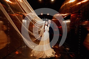 bridegroom and bride in a elegant dress, with a veil in a dark corridor