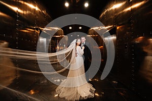 bridegroom and bride in a elegant dress, with a veil in a dark corridor