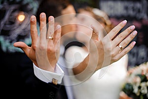 Bridegroom and bride kissing and showing wedding rings on their fingers