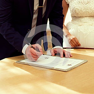 Bridegroom and bride signing marriage contract during wedding.