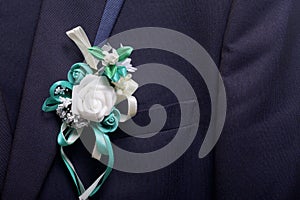 The bridegroom`s suit hangs on a hanger. On the chest attached a wedding flower.