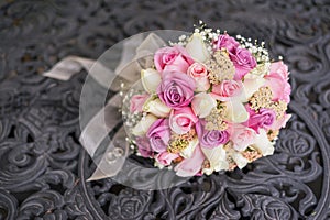 Brides bouquet made from pink and white rouses laying on iron table with wedding rings photo