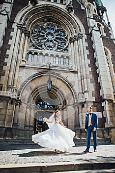 Brides dancing on the background of a Gothic church