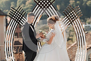 Brides and grooms stand by the golden arch during the painting ceremony