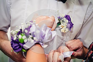 Brides hand putting the boutonniere flower on