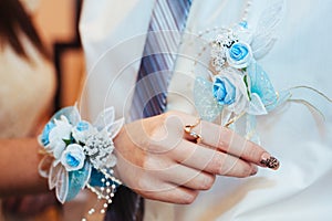 Brides hand putting the boutonniere flower on a