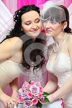 Brides look at each other and hold bouquet