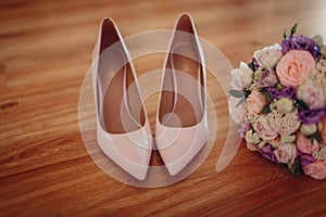 brides shoes and floral bouquet of various colorc on the wooden background