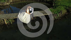 The brides sit near the lake on a small bridge in the park