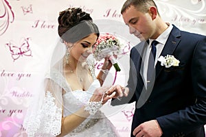 The brides wear rings near wedding banner