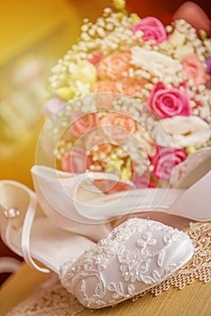Brides wedding shoes with a bouquet with roses and other flowers.
