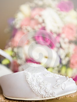 Brides wedding shoes with a bouquet with roses and other flowers.